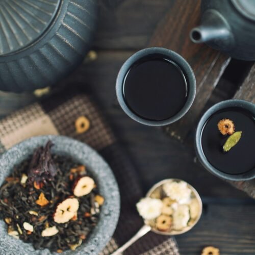 A jar and cup of golden preserve on a dark surface